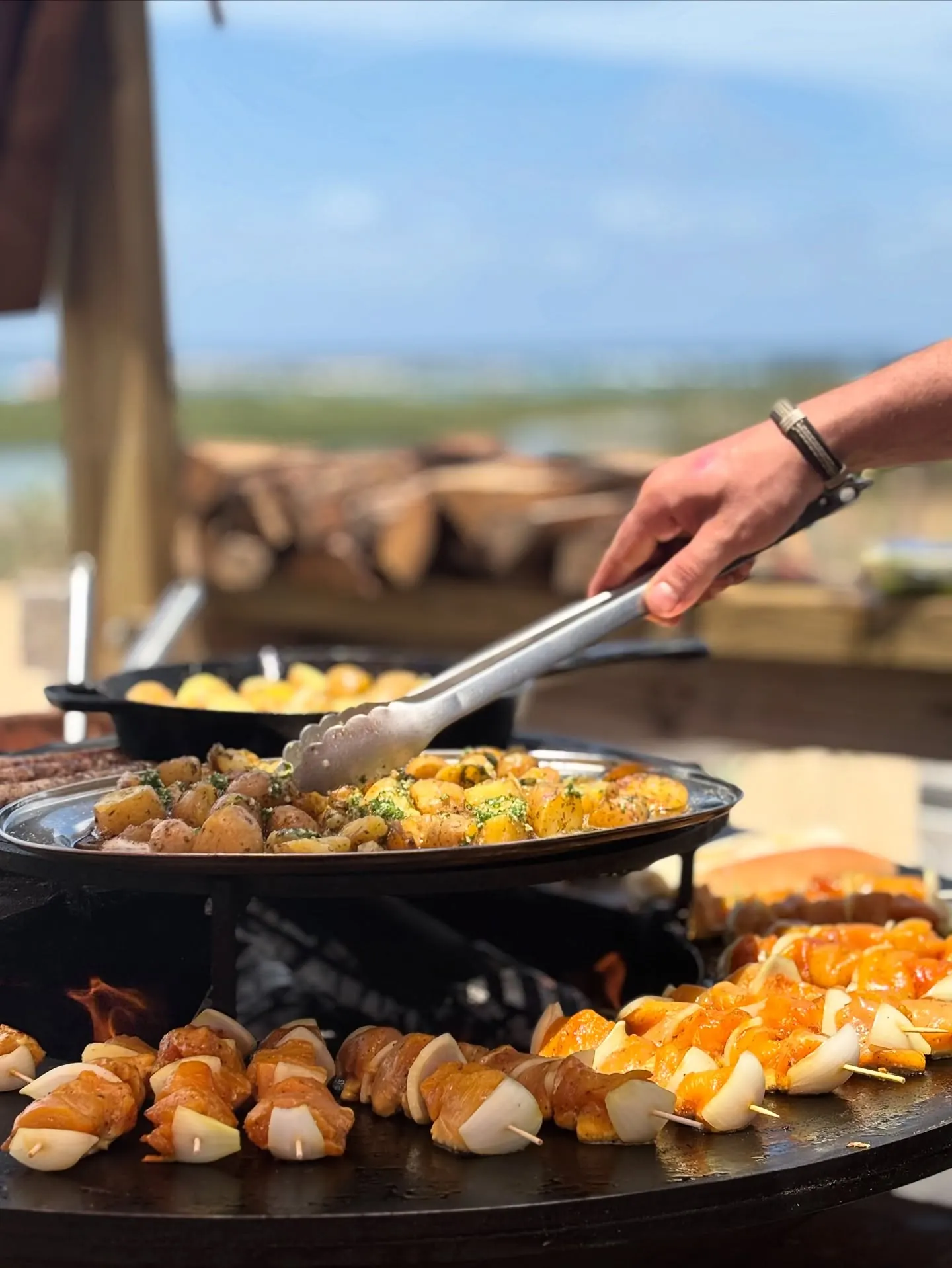 Skewers and potatoes on the fire-pit griddle